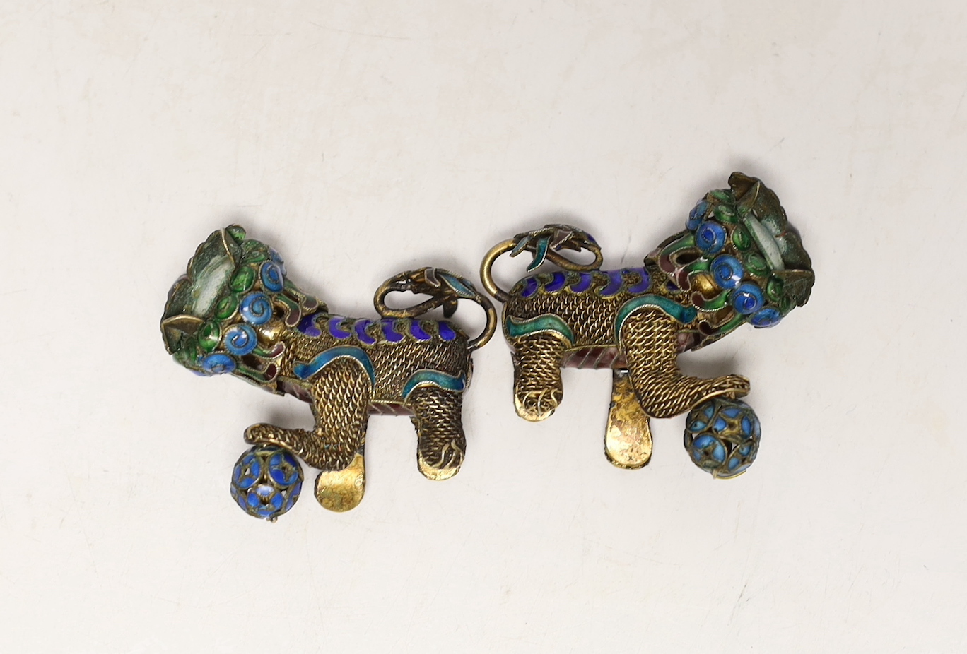 A pair of Chinese? gilt white metal and enamel Shi Shi, length 45mm.